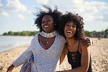 two women hugging and smiling on a beach