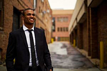 a well dressed man smiling in an alley