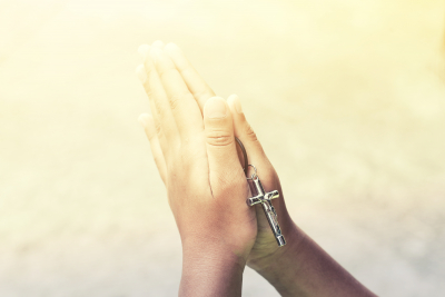 hands in praying mode with cross pendant